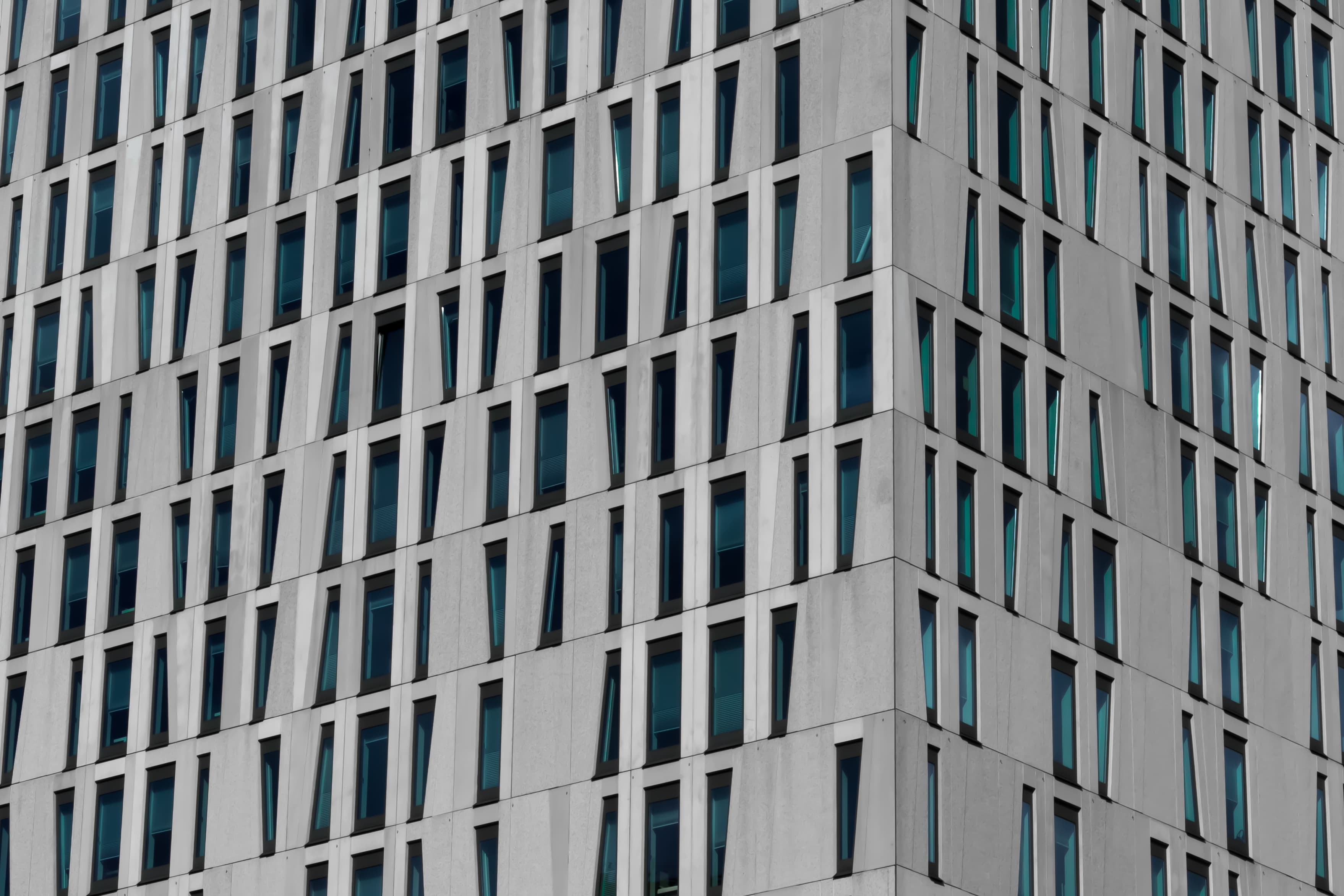 A modern office facade with narrow dark windows set into a repeating concrete grid.
