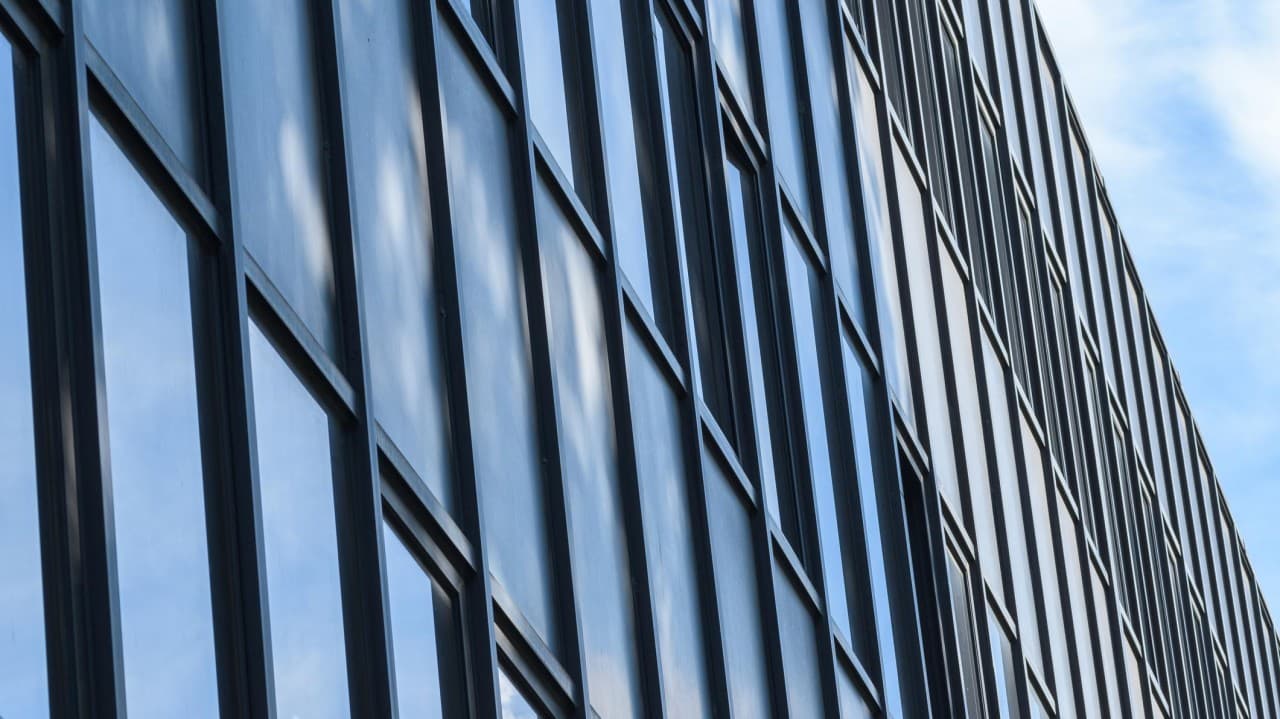 Glass office facade reflecting the sky.